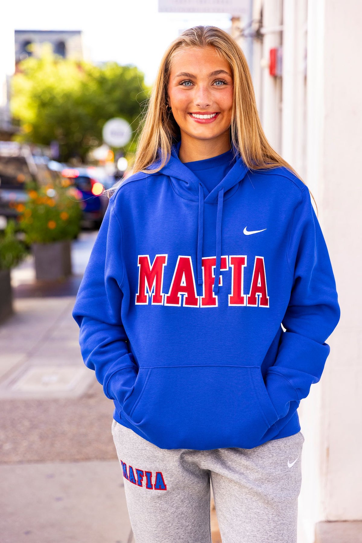 Female model wearing royal blue MAFIA hoodie with sewn-on lettering